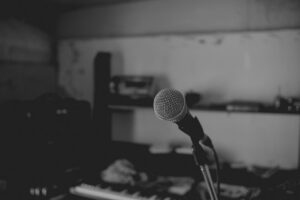 Close-up of a microphone on a stand in a dimly lit recording studio.